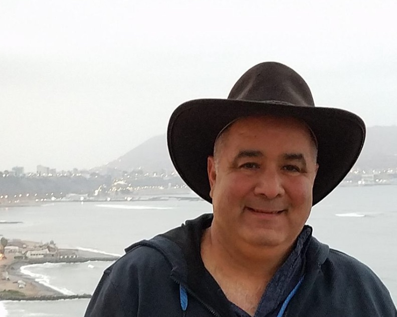 Dr. Victor Medina smiling with a backdrop of a misty coast.